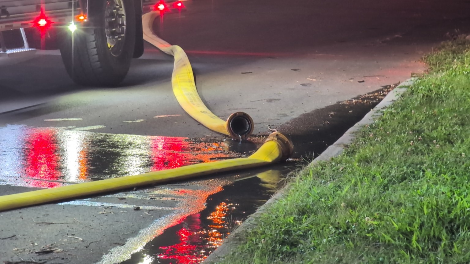 Fire hose and response equipment along a wet street.