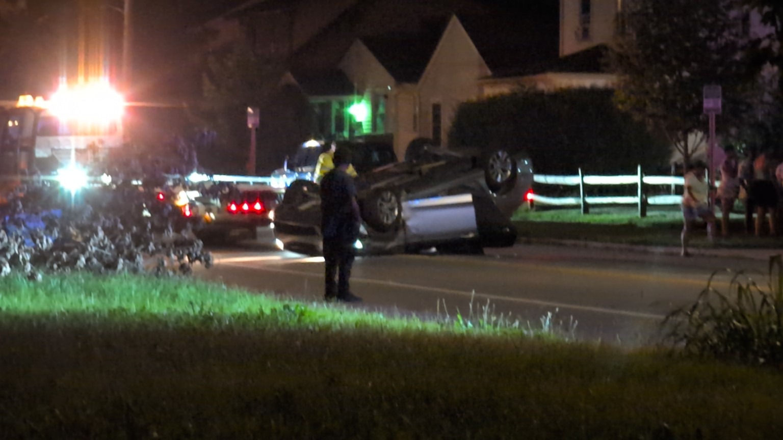 Response vehicles and a vehicle on its side after dark.