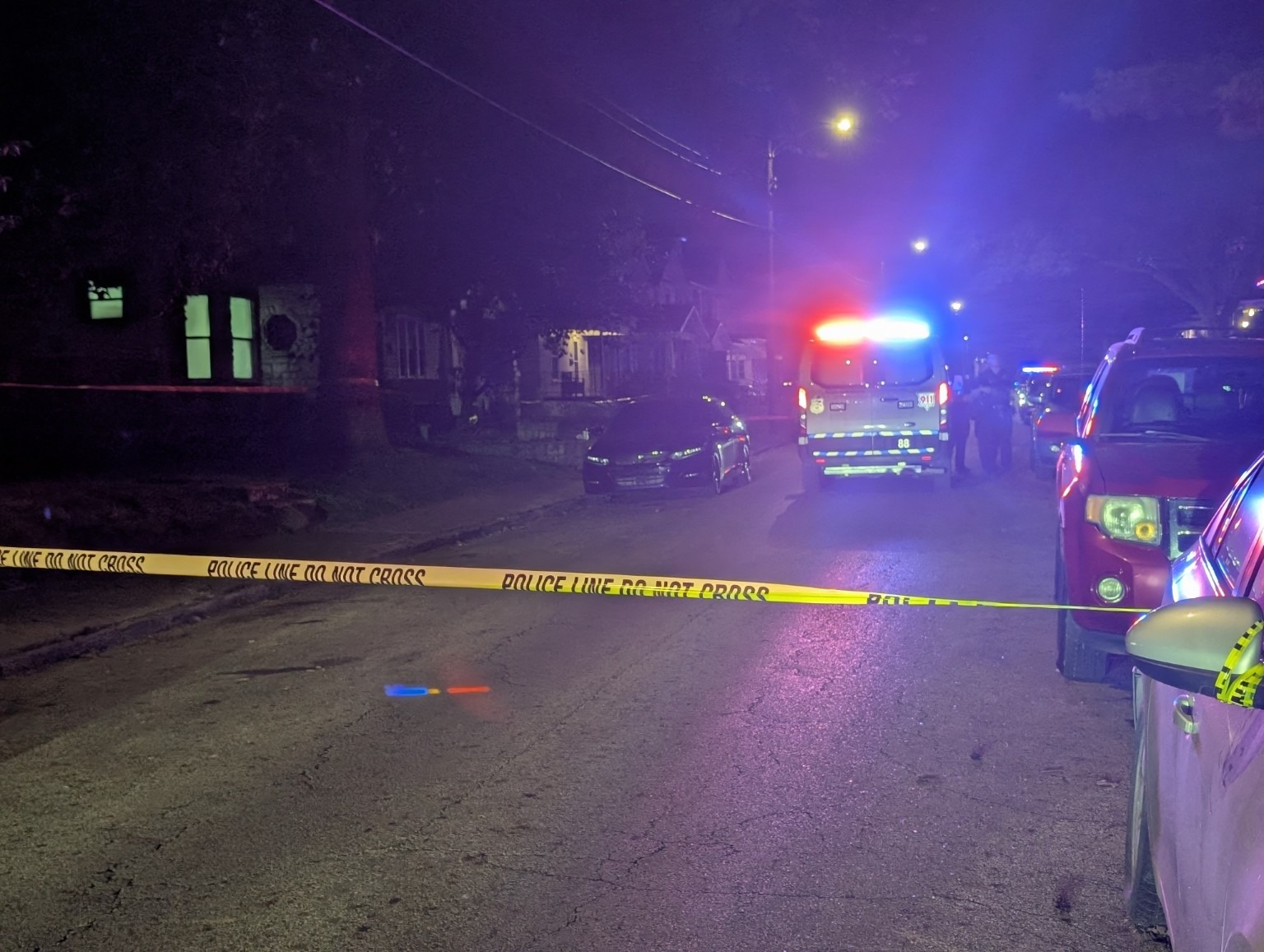 Emergency lights and yellow tape on a residential street.